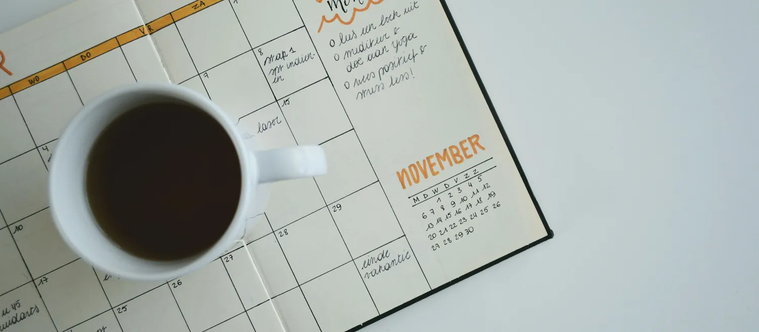 Agenda ouvert et tasse de café sur une table