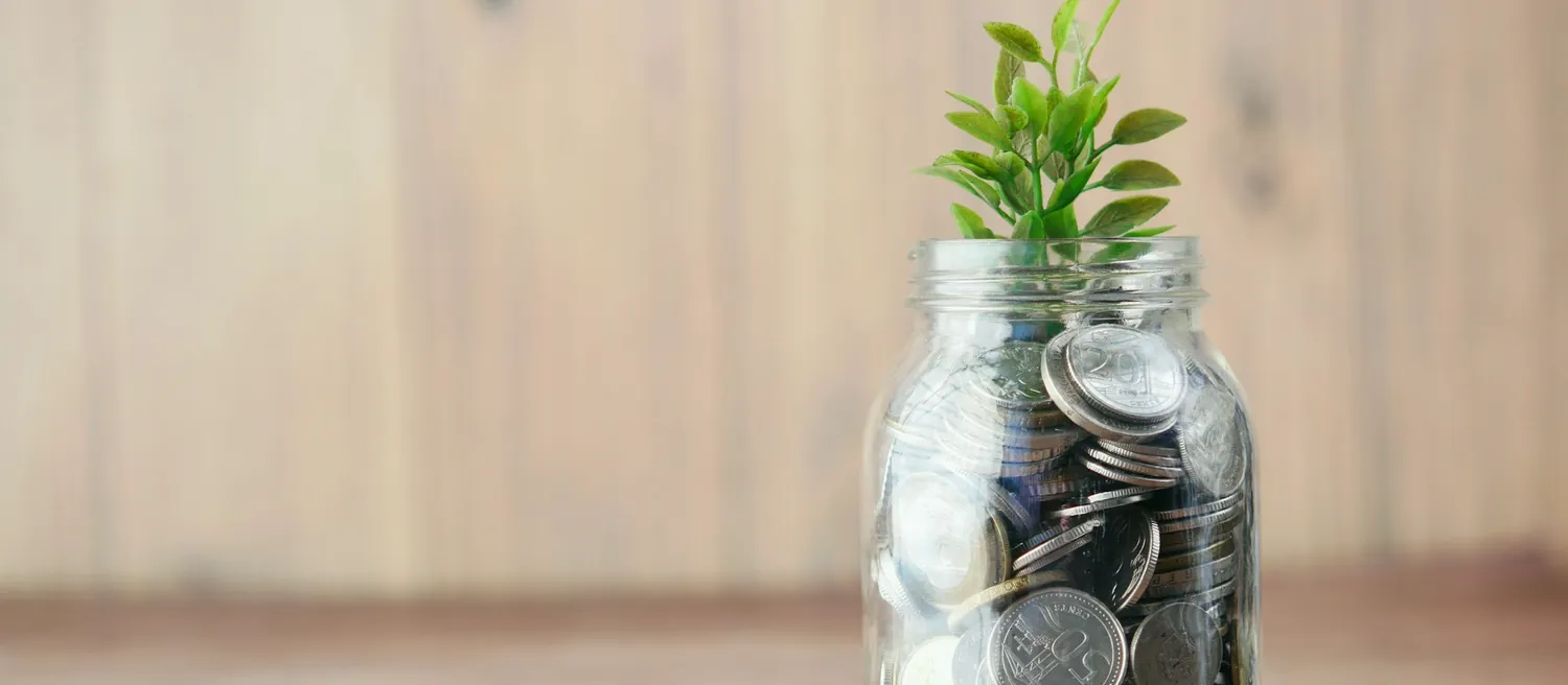 Bocal de pièces de monnaie d’où sort une jeune pousse