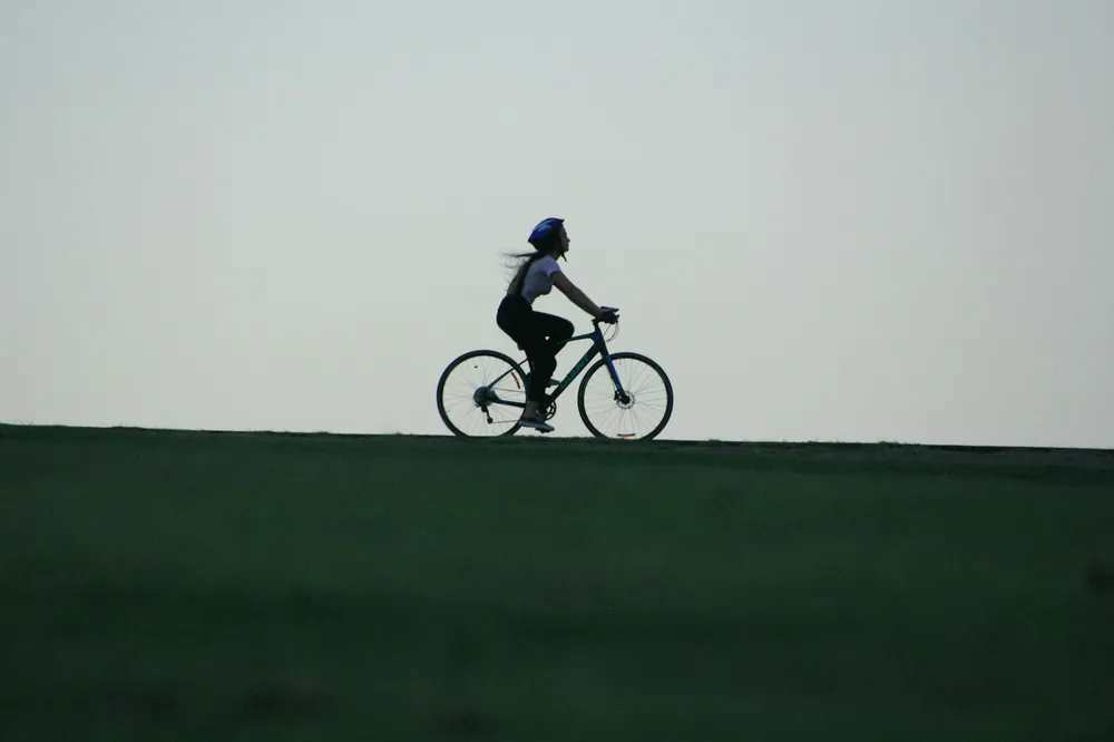 Cycliste en silhouette sur une route au lever du jour