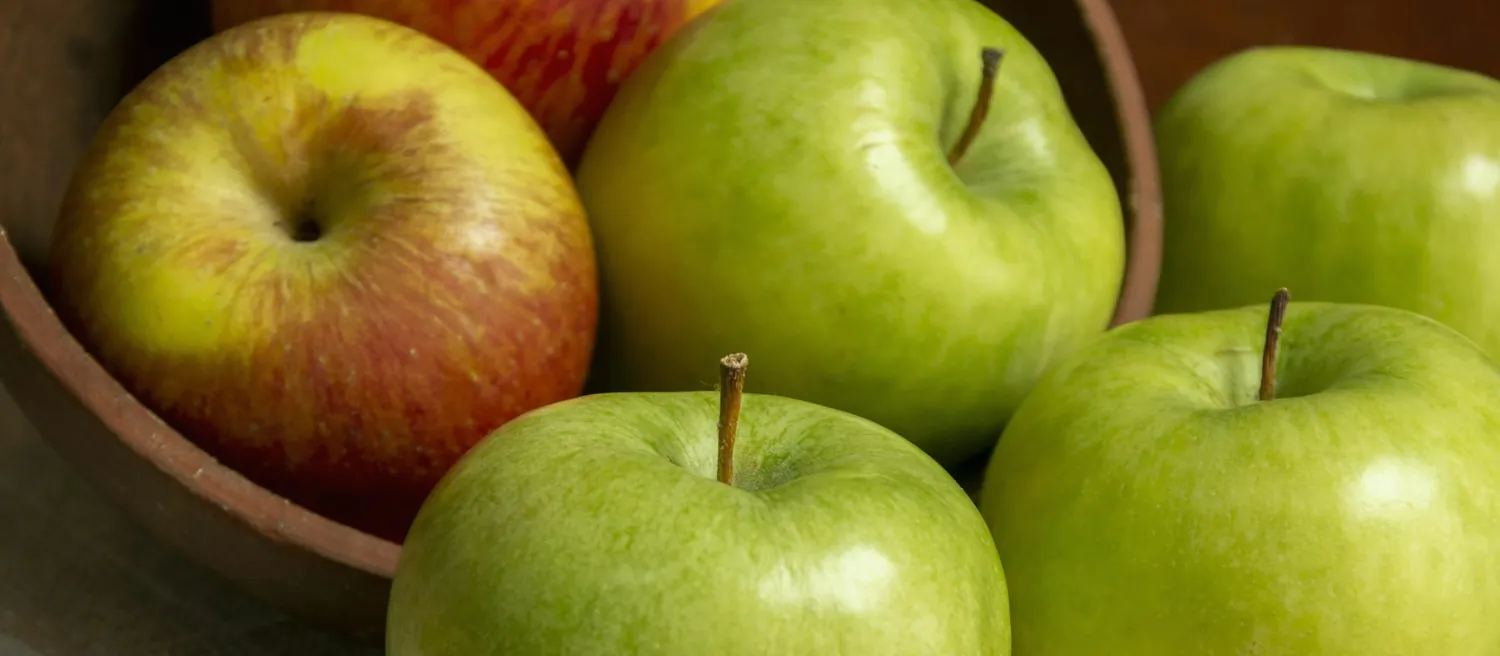 Pommes vertes et rouges dans une corbeille en bois